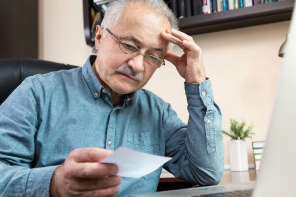 a man holding a pen and looking at a laptop