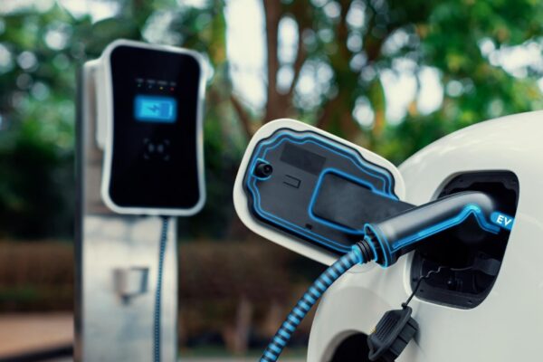Electric car plugged in with charging station to recharge battery with electricity by EV charger cable in eco green park and greenery foliage Future innovative ev car and energy sustainabilityPeruse
