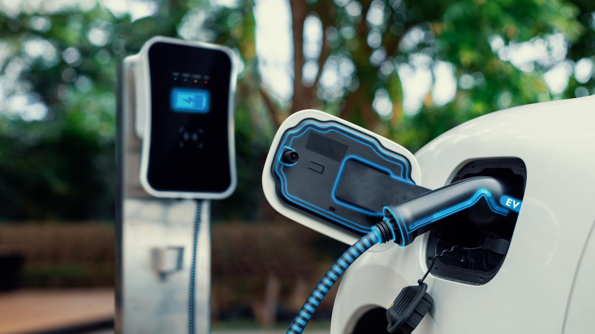 Electric car plugged in with charging station to recharge battery with electricity by EV charger cable in eco green park and greenery foliage Future innovative ev car and energy sustainabilityPeruse