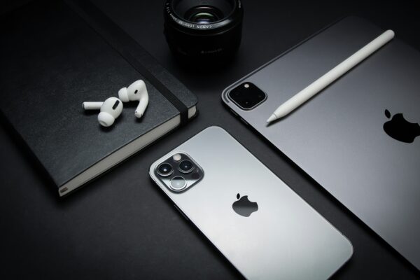 silver macbook beside black camera lens and black camera lens
