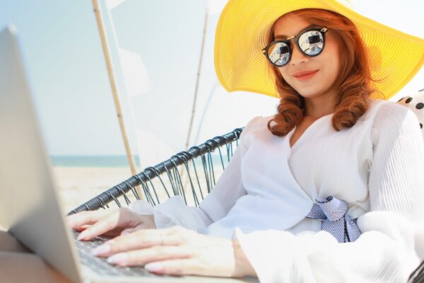 Woman sitting and using computer on beach chair