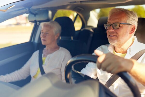 road trip, travel and old people concept - happy senior couple driving in car