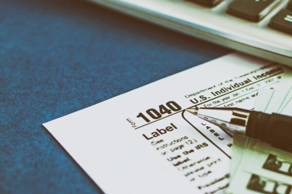 Tax form 1040 pen calculator and dollars on a blue table The concept of business taxation and business