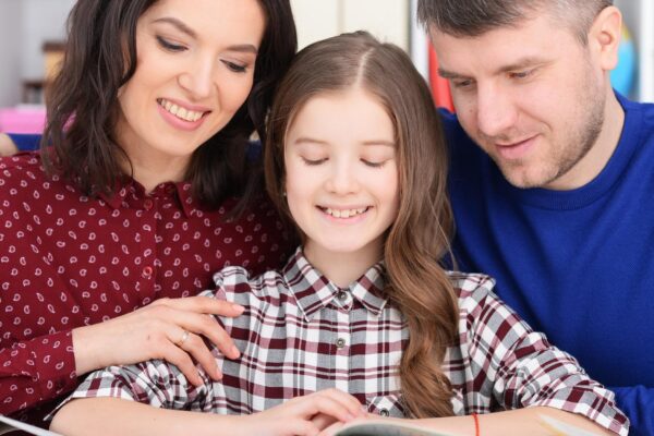 parents and daughter doing homework in room