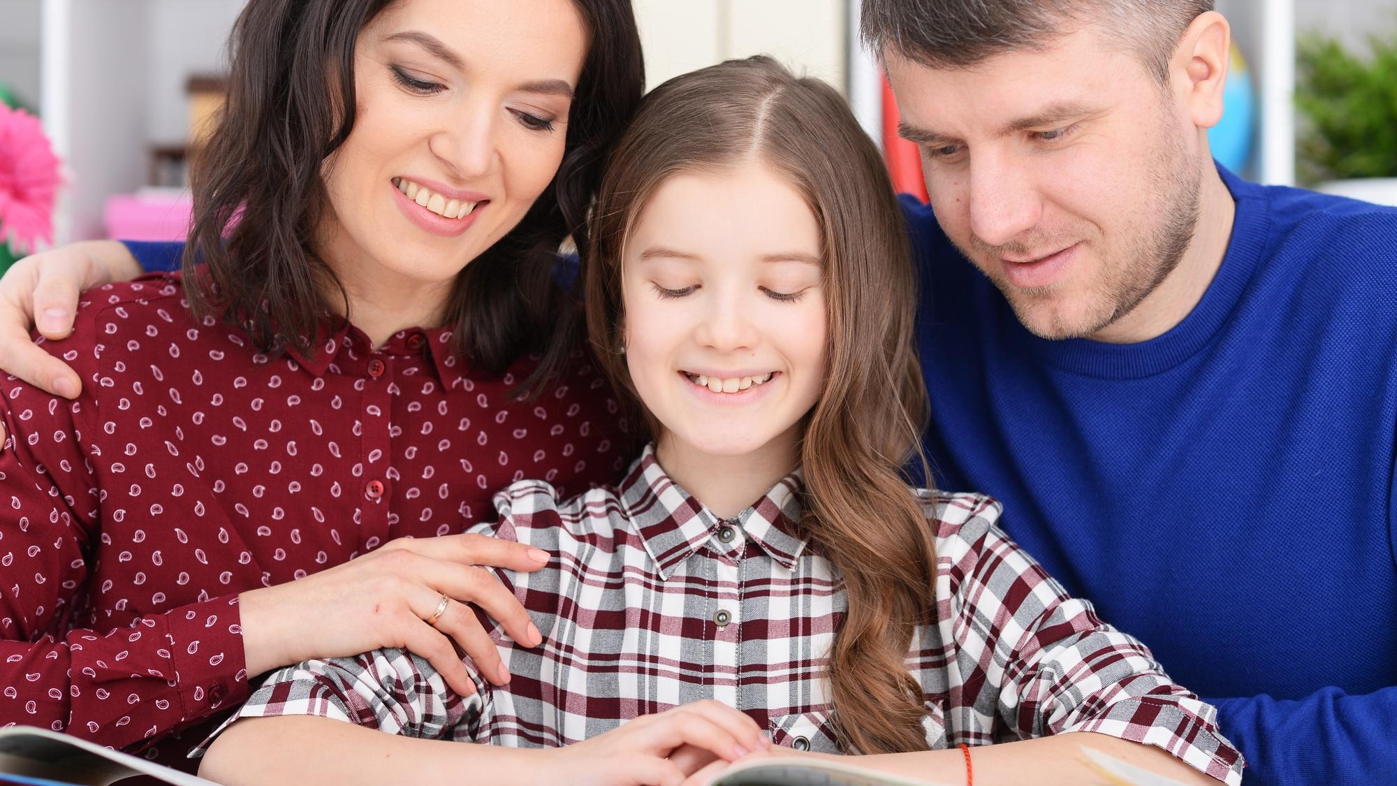 parents and daughter doing homework in room