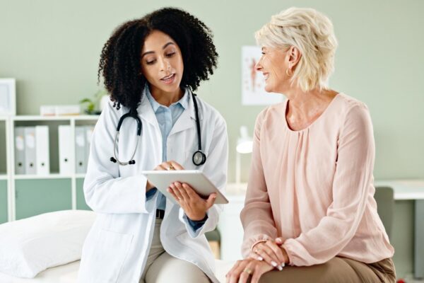 Woman doctor and consulting patient with tablet in checkup for medical results diagnosis or prescription at hospital Female person talking to client for consultation help or advice at clinic