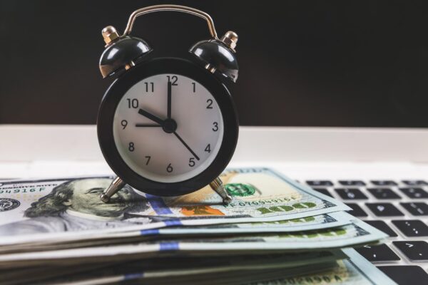 Closeup of an alarm clock with dollars on a laptop keyboard Online shopping concept