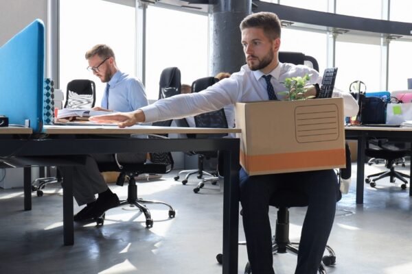 Sad dismissed worker are taking his office supplies with him from office.