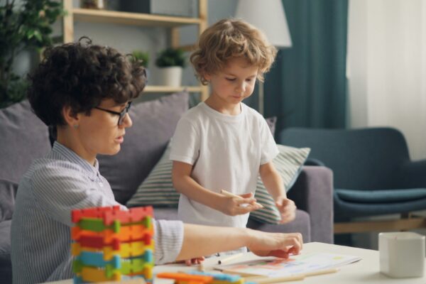 a woman and a child playing with blocks on a table