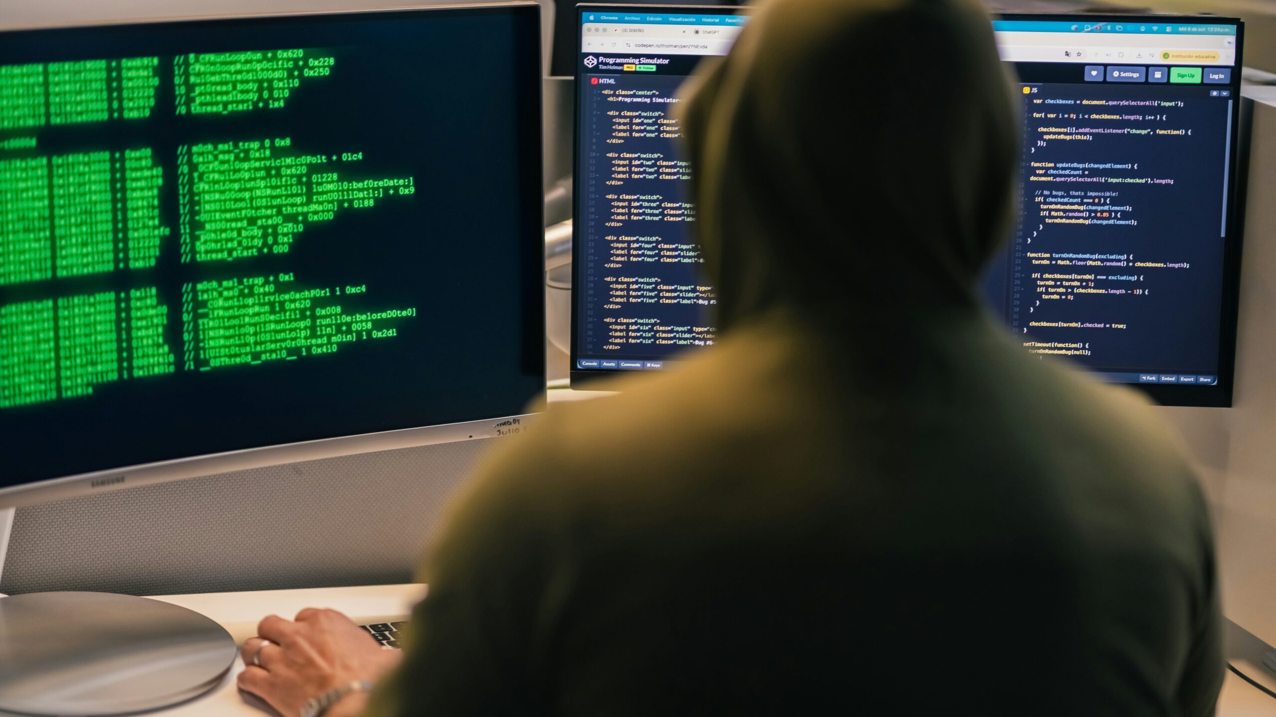 Hacker in hoodie working on multiple computer screens