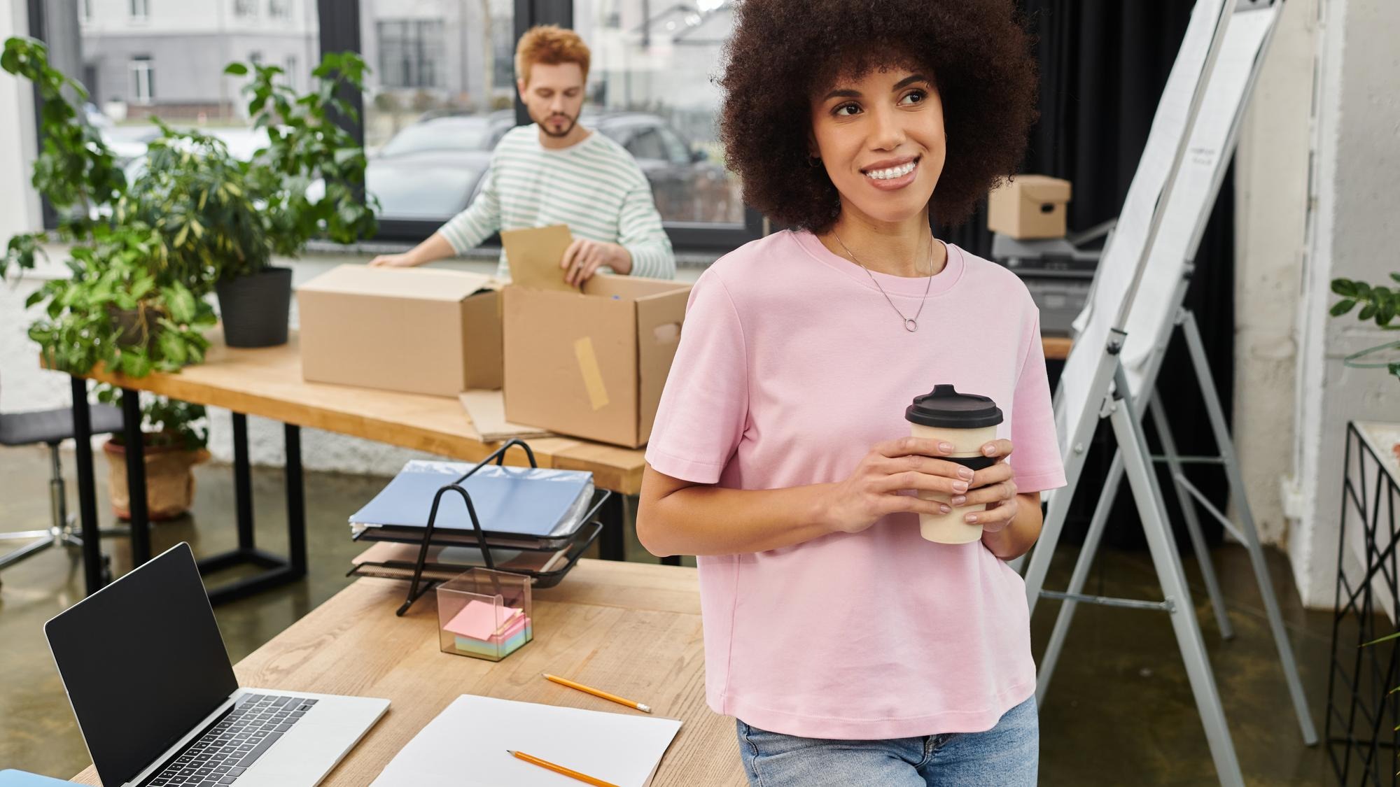 Brightly lit modern workspace featuring individuals packing and sipping coffee during a moving day