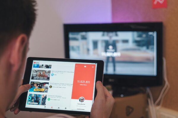 man browsing tablet sitting in front of TV