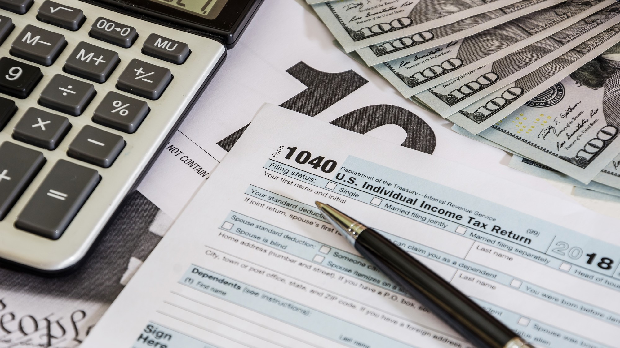 tax forms 1040 and calculator with dollars
