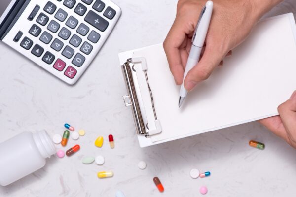 Healthcare costs concept. Opened medicine bottle and spilled out capsules on table.