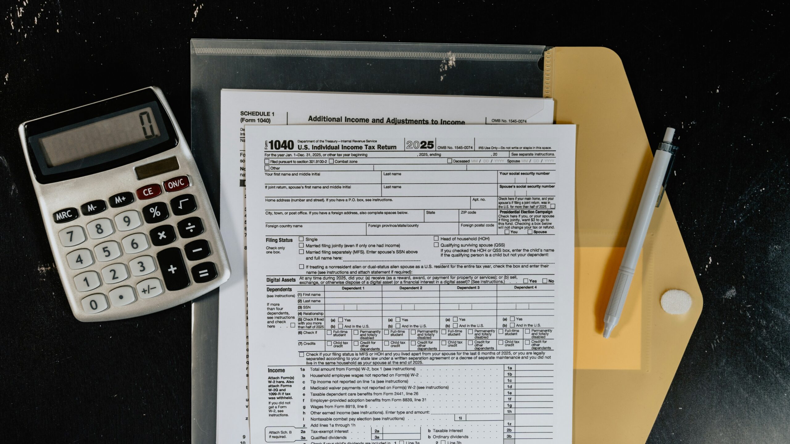 Calculator and tax forms on a dark surface.