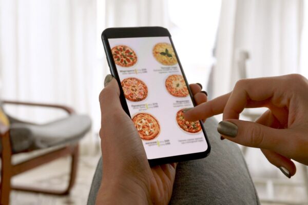 Woman browsing smartphone screen ordering pizza at home online