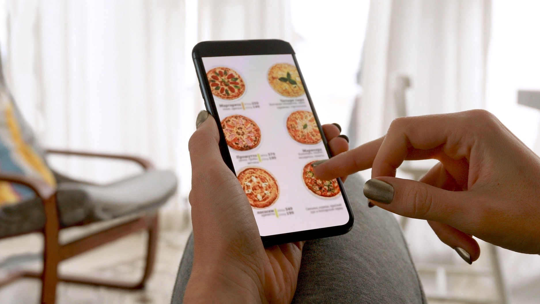 Woman browsing smartphone screen ordering pizza at home online