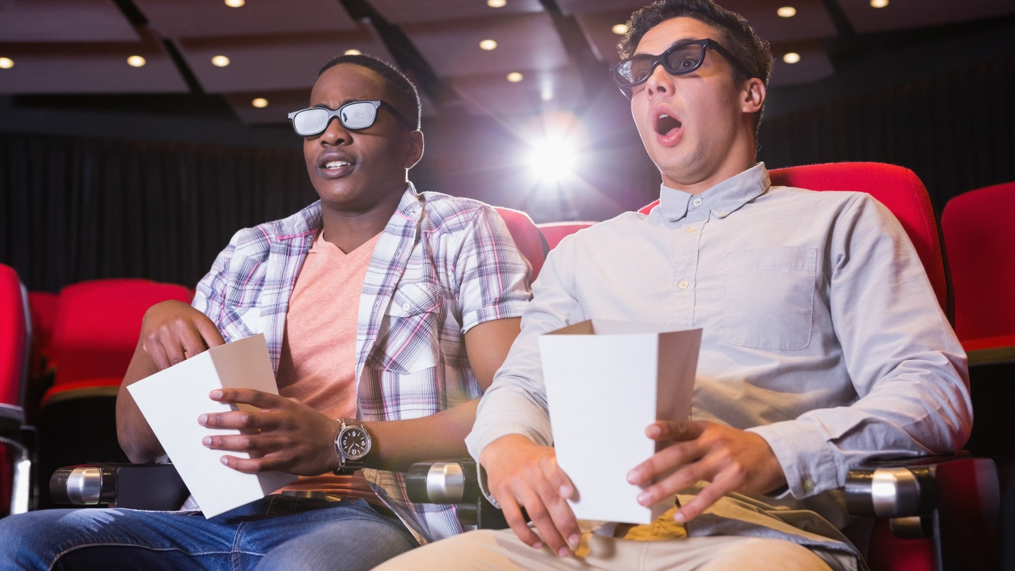 Astonished young friends watching 3d film
