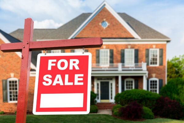 For sale sign in front of large USA home