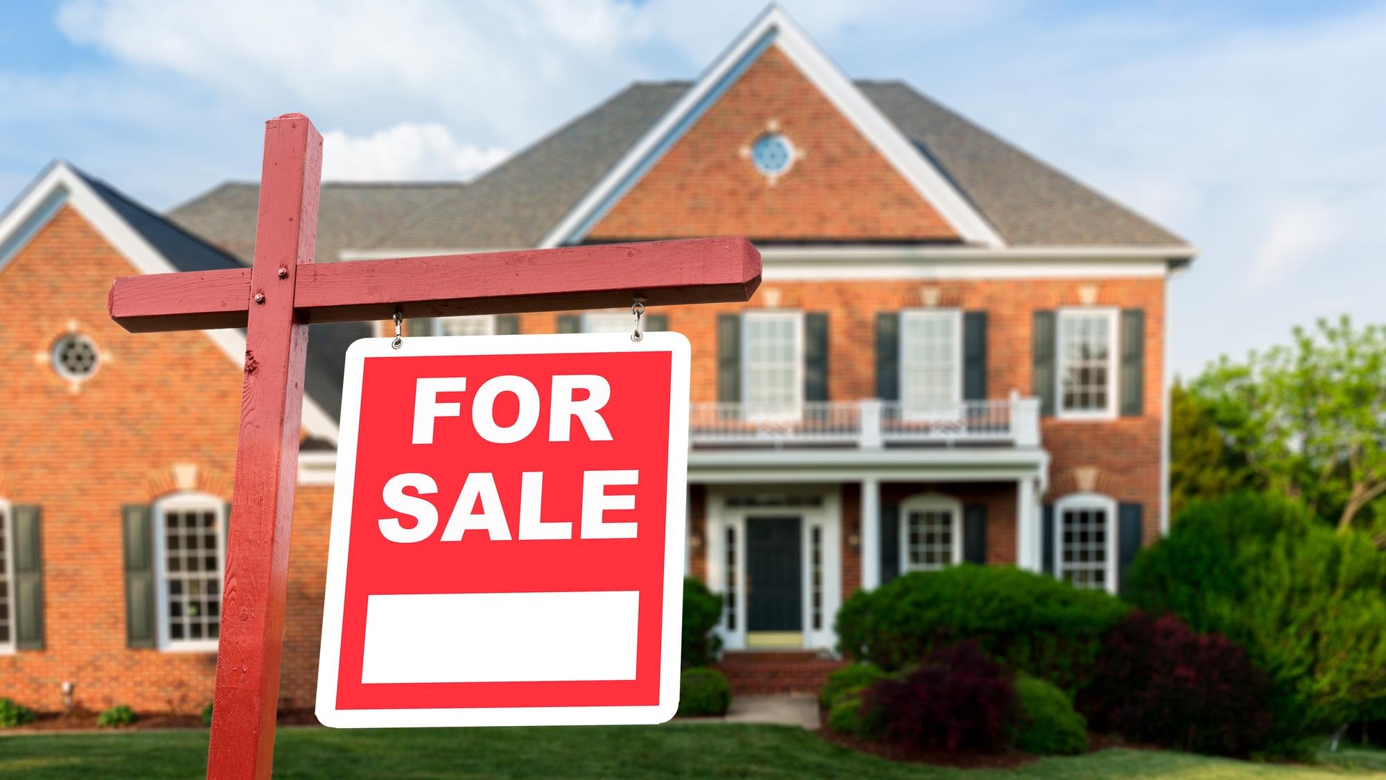 For sale sign in front of large USA home