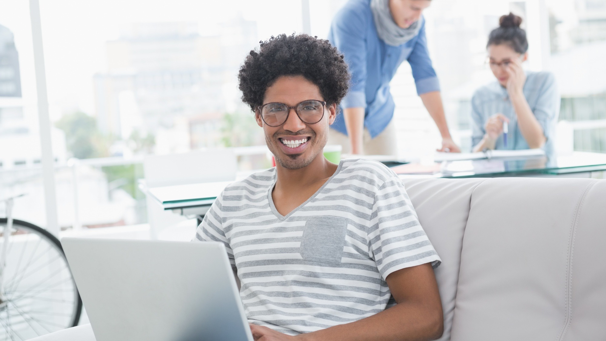 Young creative man using laptop on couch