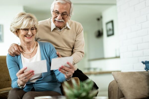 Happy mature woman and her husband looking at their photos while relaxing at home