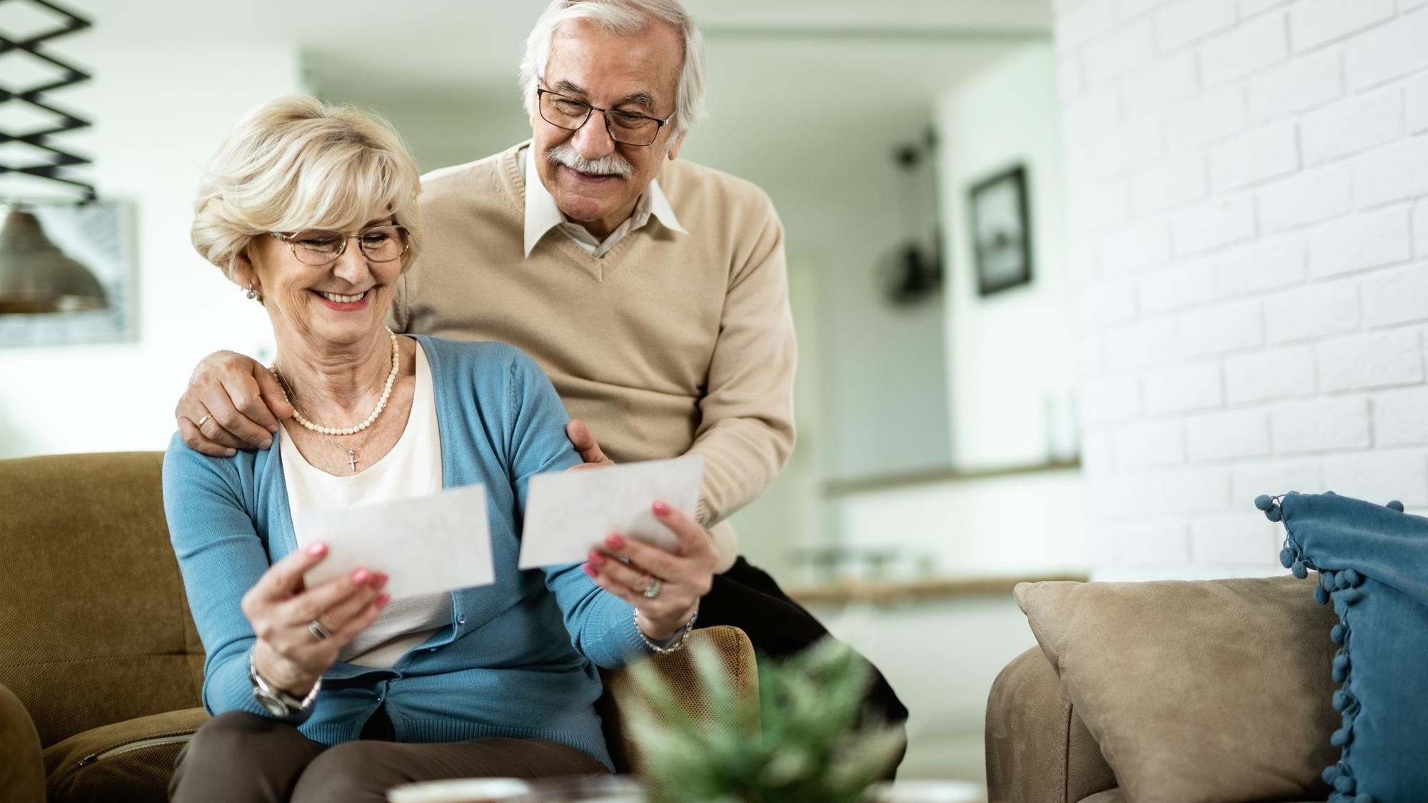 Happy mature woman and her husband looking at their photos while relaxing at home