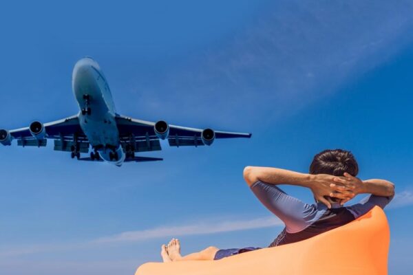 Man tourist have fun on the beach watching the landing planes traveling on an airplane concept text