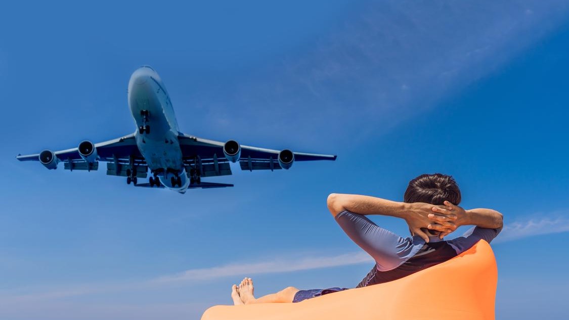 Man tourist have fun on the beach watching the landing planes traveling on an airplane concept text