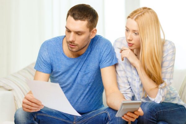 tax, finances, family, home and happiness concept - busy couple with papers and calculator at home