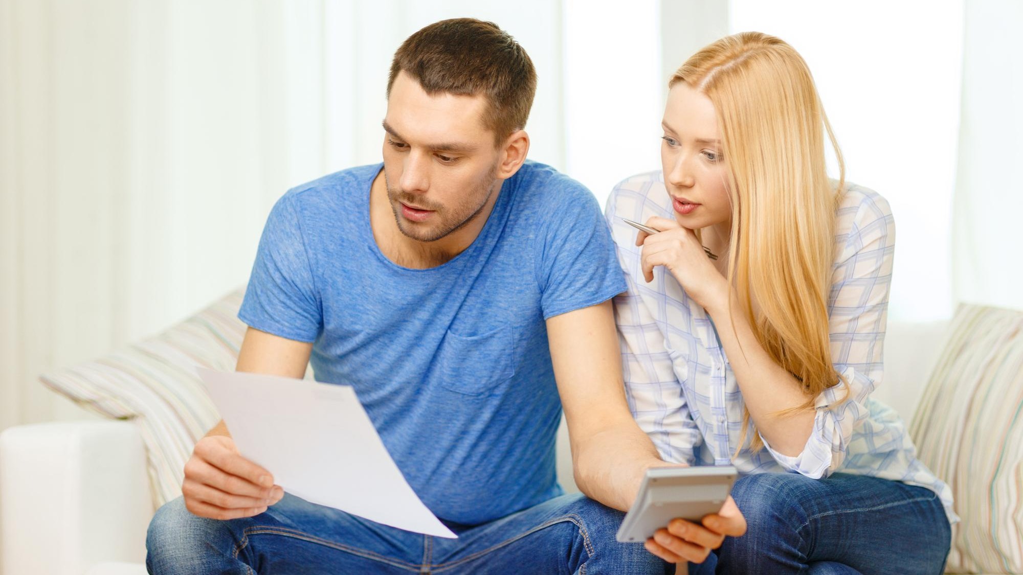 tax, finances, family, home and happiness concept - busy couple with papers and calculator at home