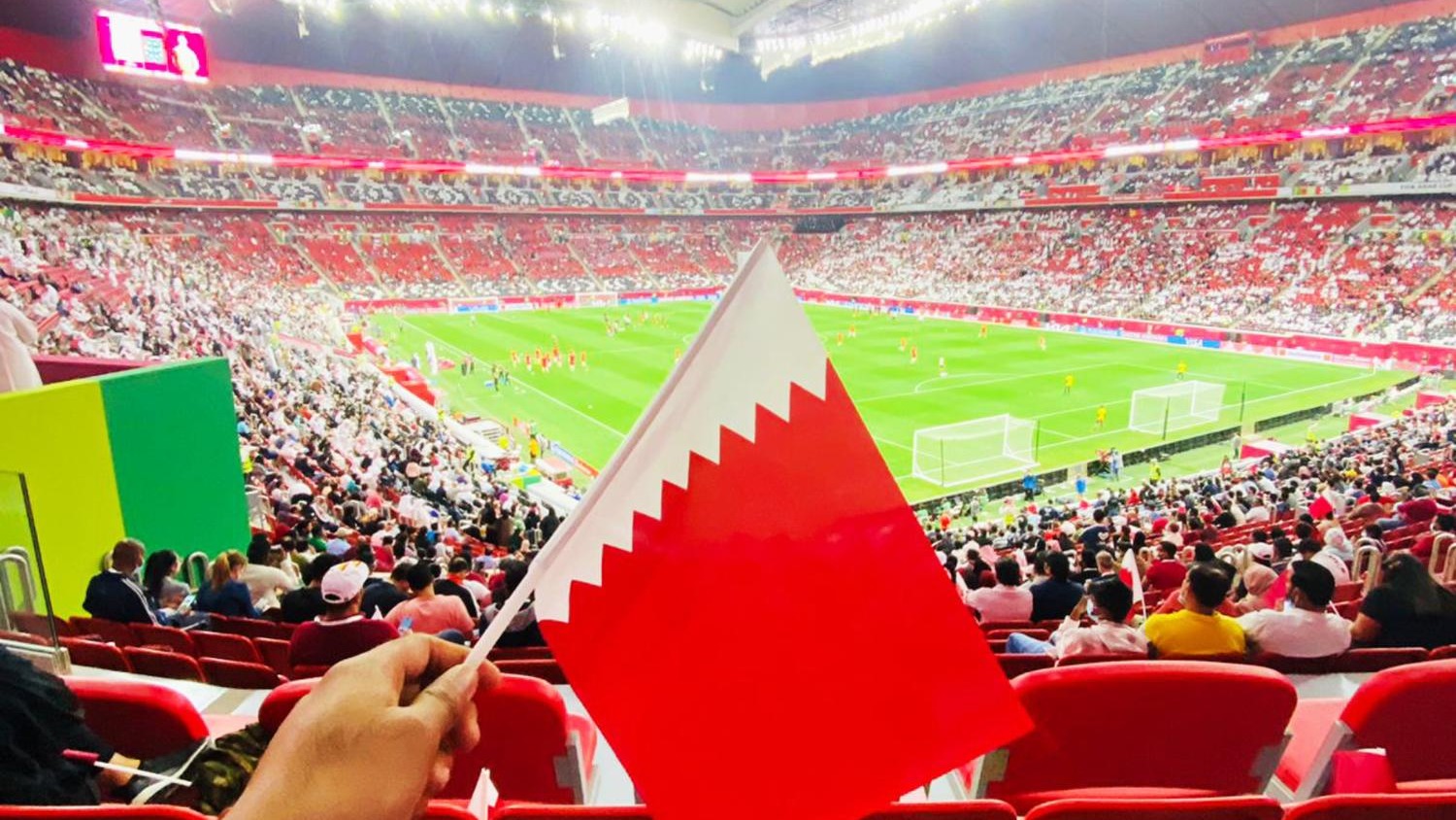 A scene during the FIFA Arab Cup where an enthusiastic fan waves the Qatari flag