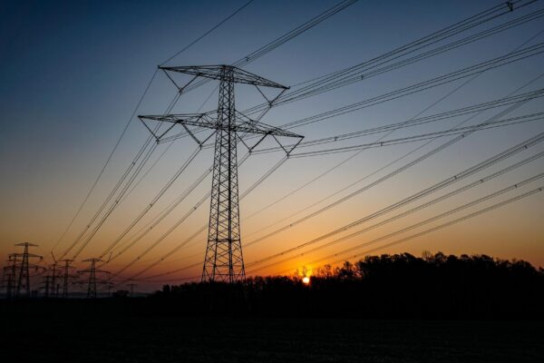 Low angle view of electricity pylon against sky during sunset
