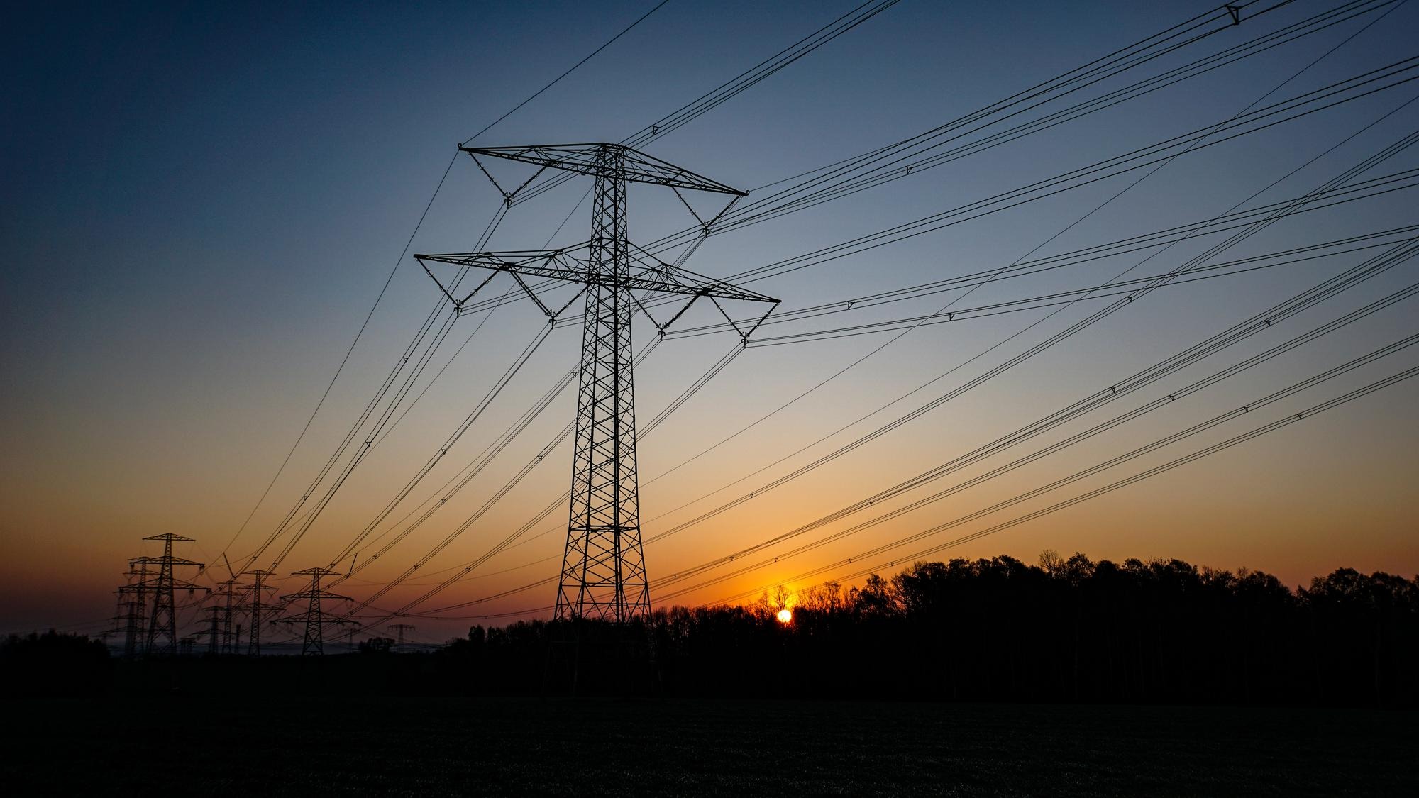 Low angle view of electricity pylon against sky during sunset