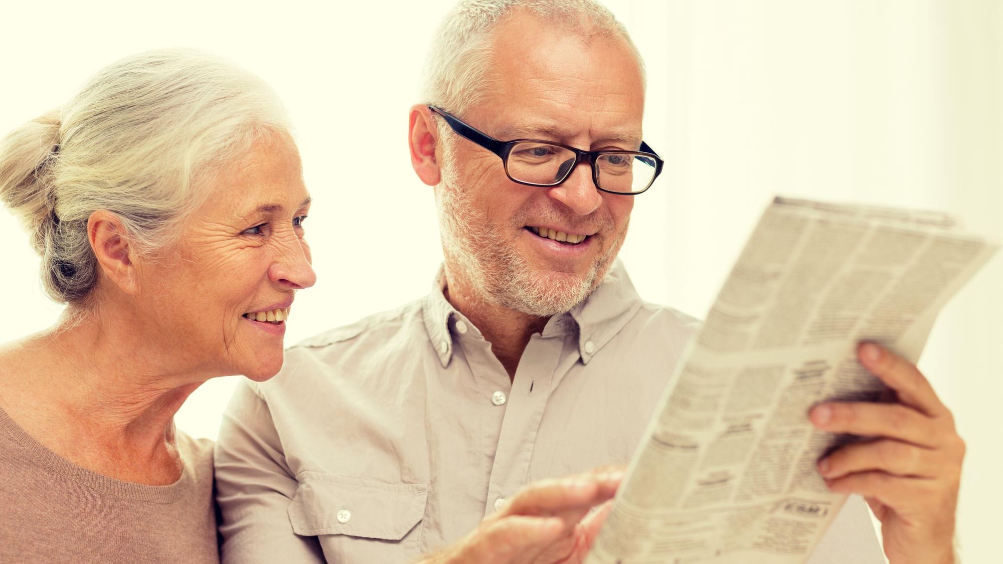 family, holidays, age and people concept - happy senior couple reading newspaper at home