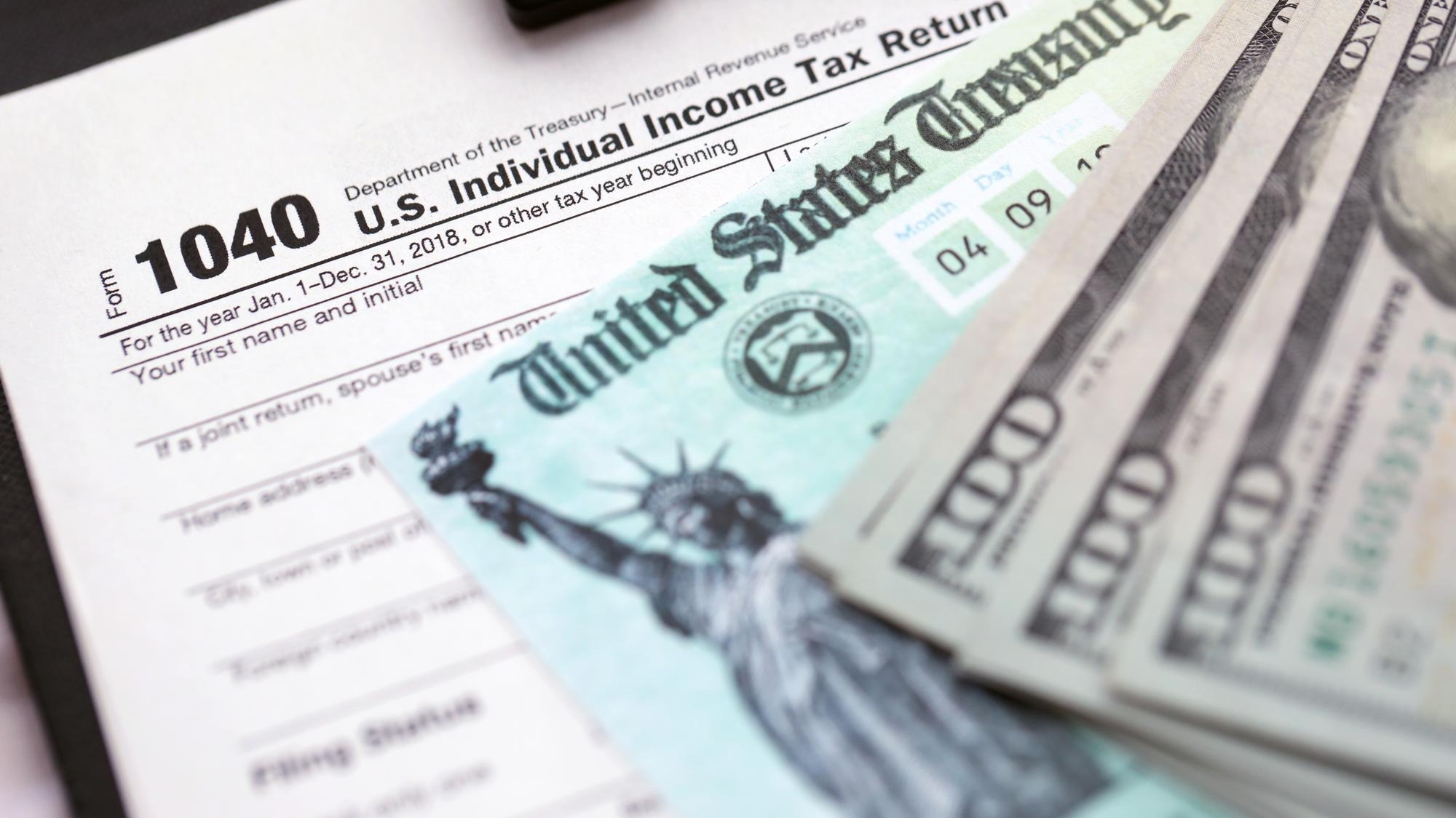 United states tax form individual income tax return with refund check and us dollar bills close up