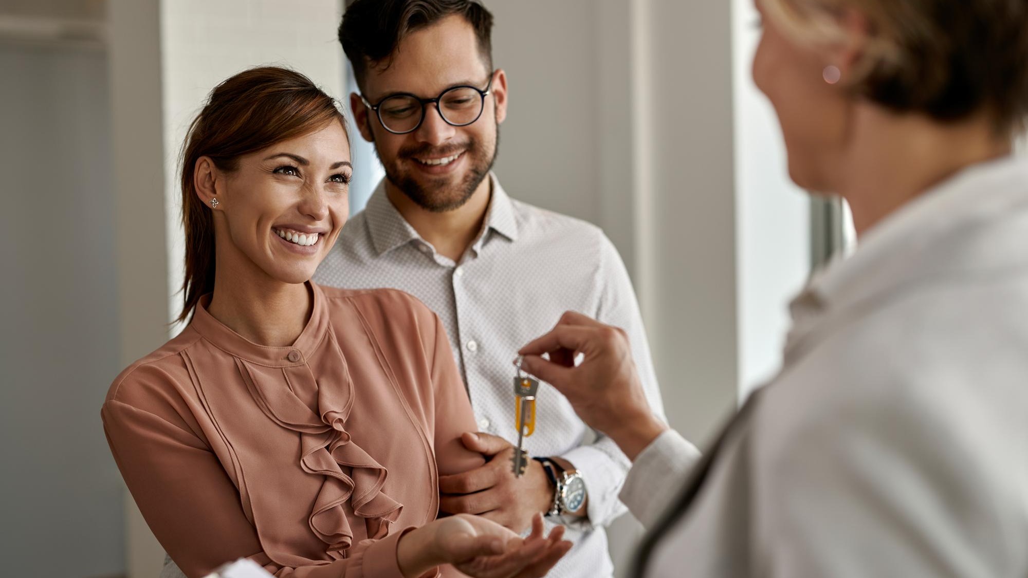 Happy couple buying their new home and receiving keys from real estate agent