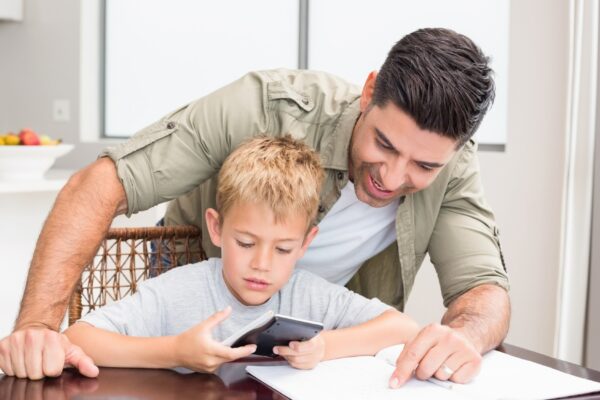 Smiling father helping son with math homework at table