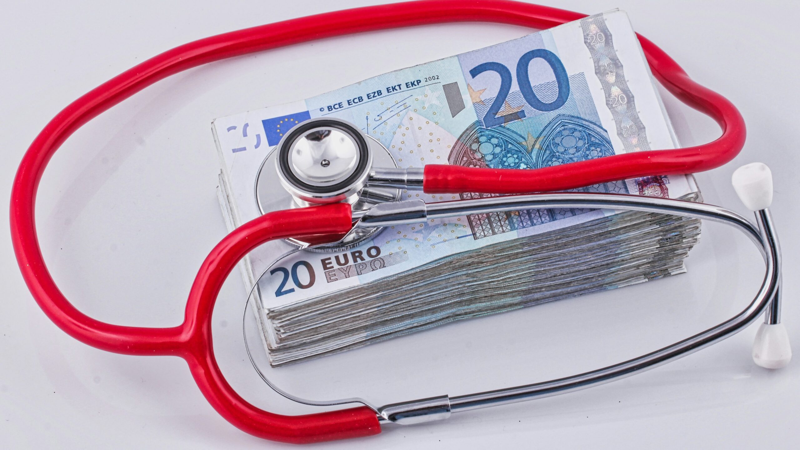 a red stethoscope sitting on top of a pile of money