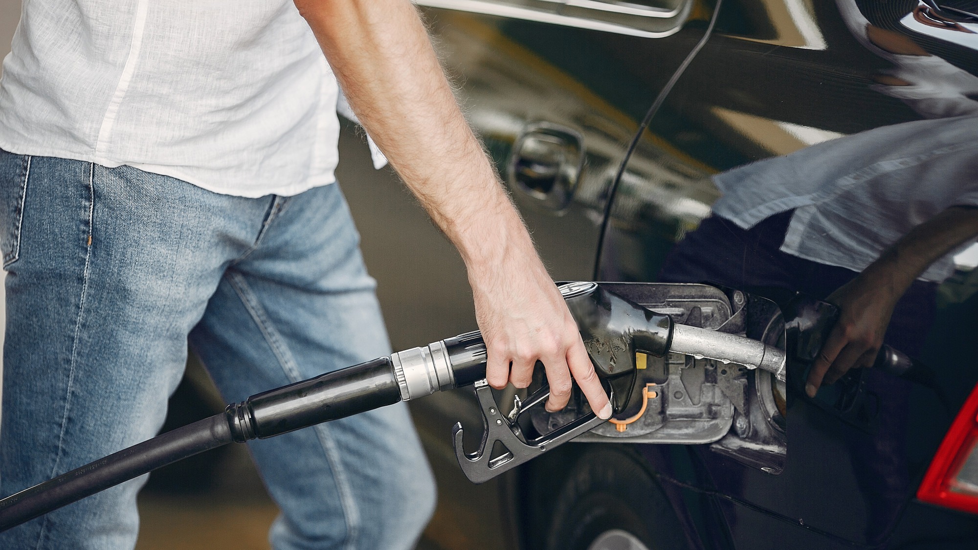 Handsome man pours gasoline into tank of car