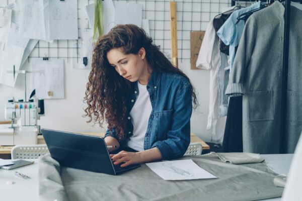 Fashion designer working on a laptop in her studio.