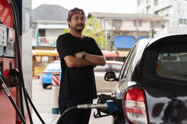 Portrait of a smiling businessman refueling his luxury car at the gas station Man driver hand refilling and pumping gasoline oil the car with fuel at he refuel station
