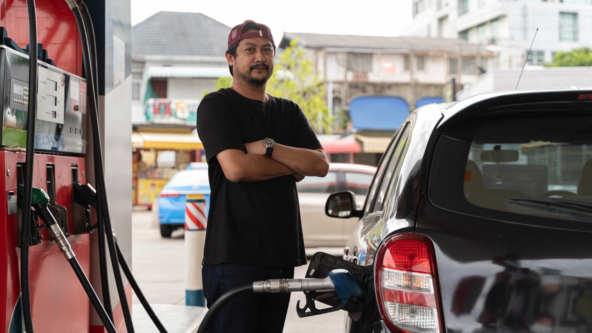 Portrait of a smiling businessman refueling his luxury car at the gas station Man driver hand refilling and pumping gasoline oil the car with fuel at he refuel station