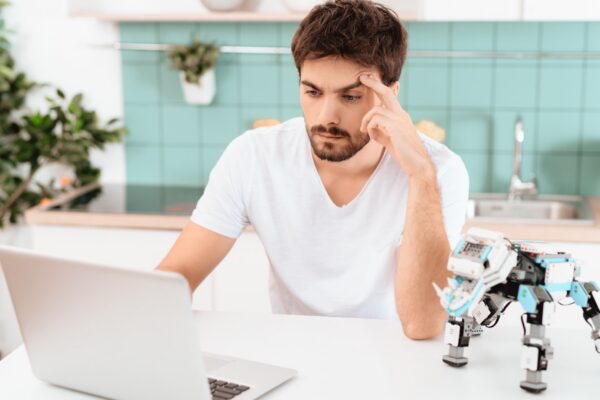 A man is programming a robot in the kitchen