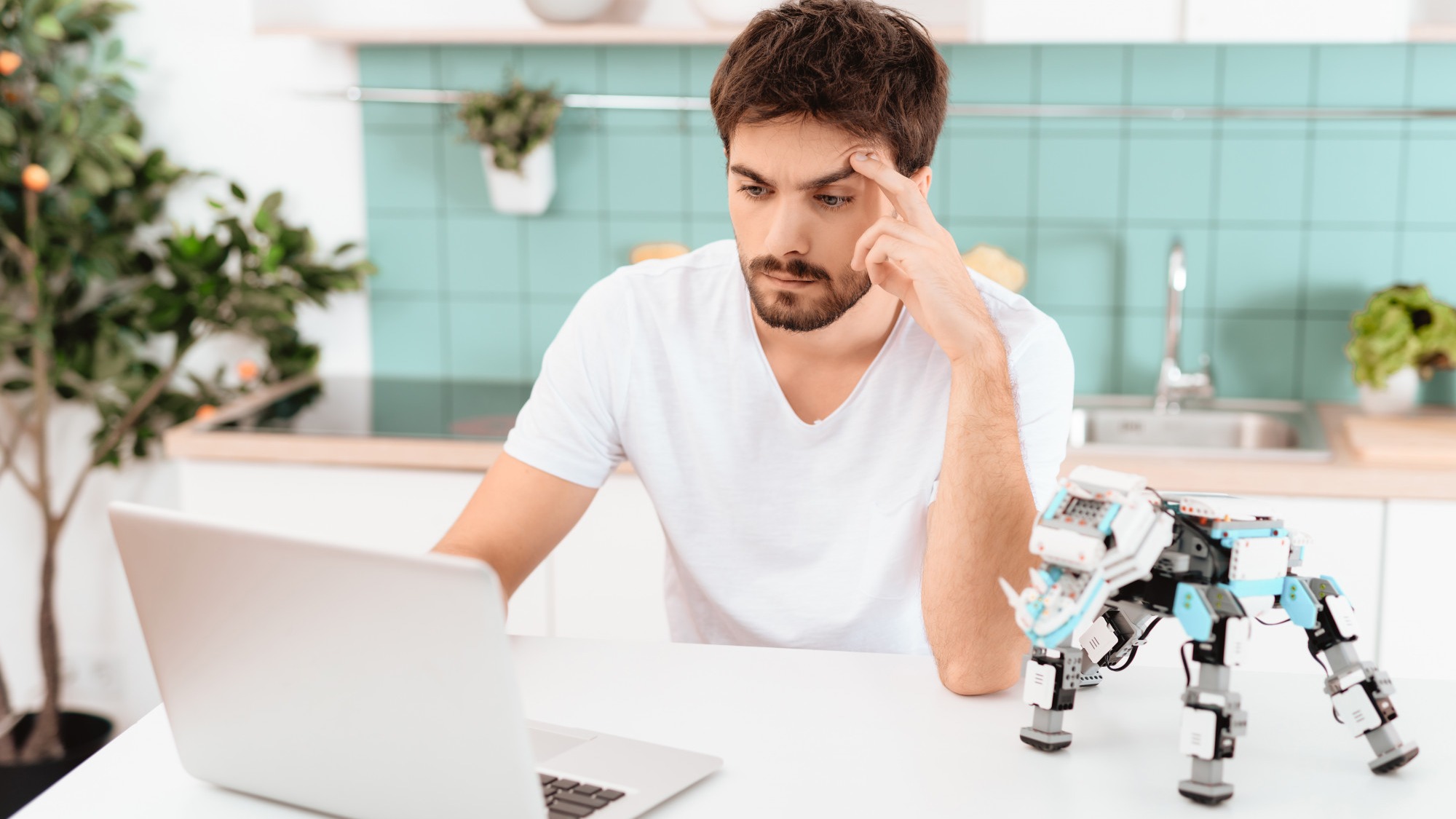 A man is programming a robot in the kitchen