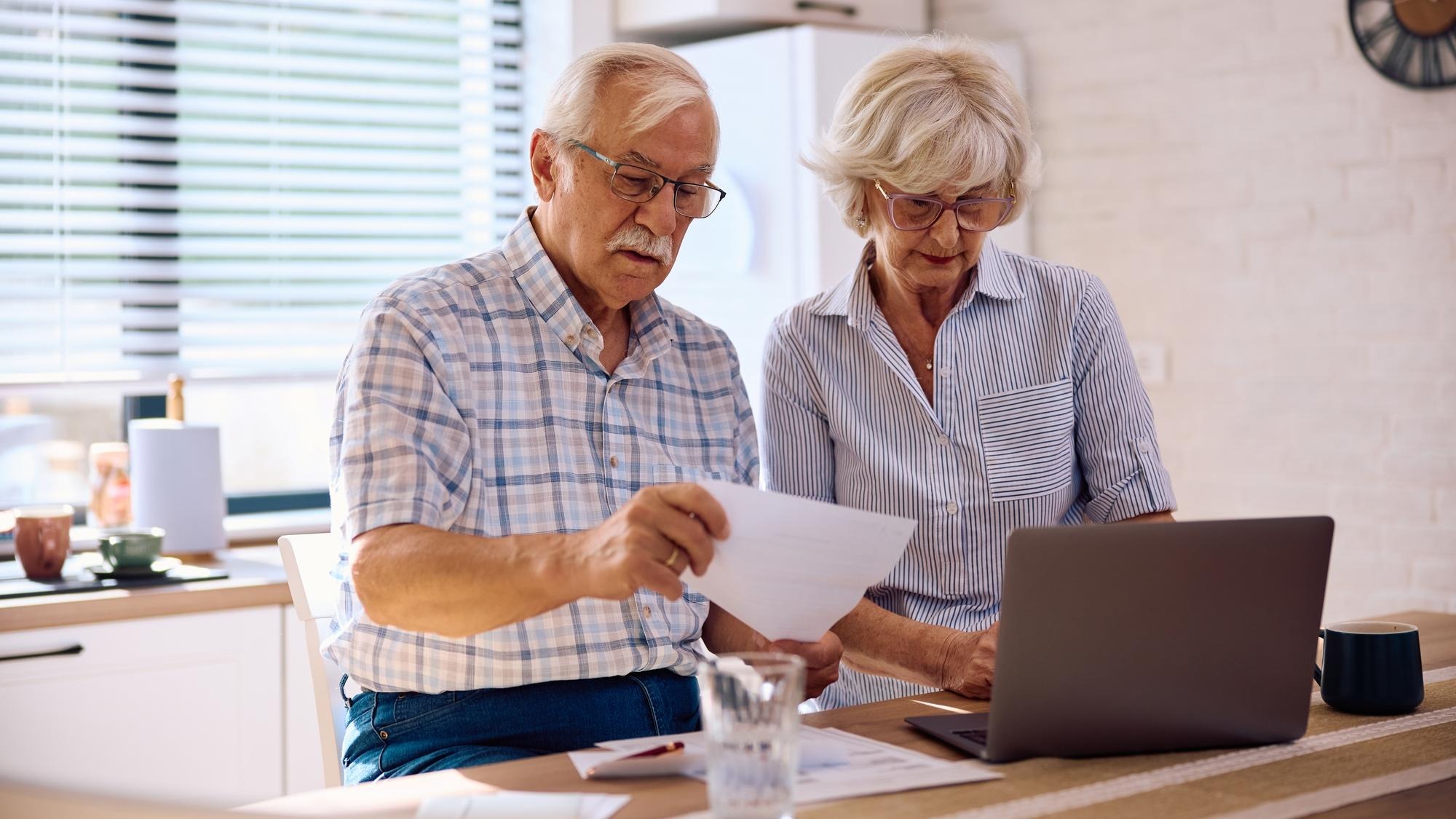 Senior couple planning their household budget while using laptop at home