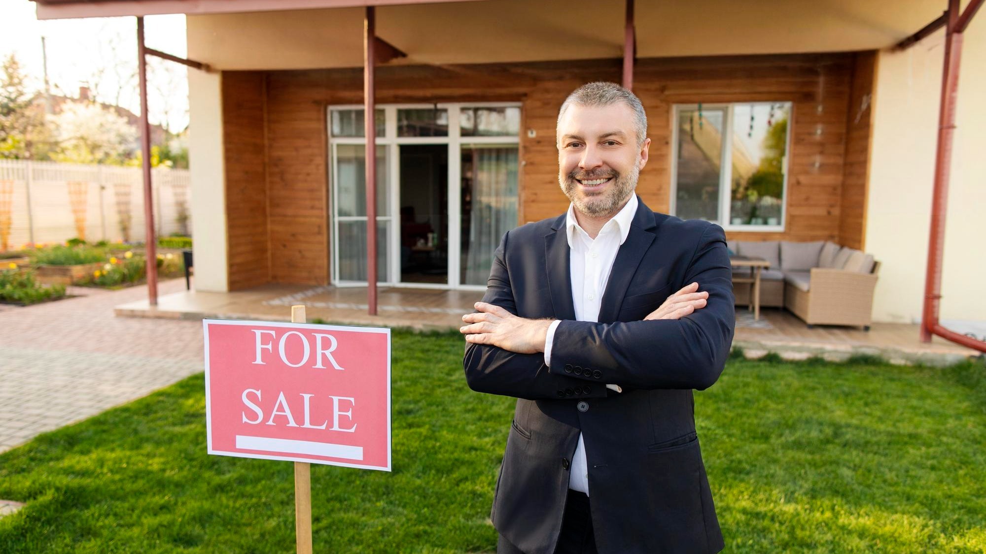 Happy middle aged european real estate agent standing outdoors in front of new house for sale