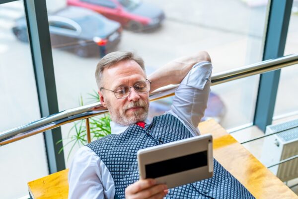 Brainstorming. Man laying at table with tablet in hands. Searching for ideas in internet. The concept of business, computer work, distant work freelance.