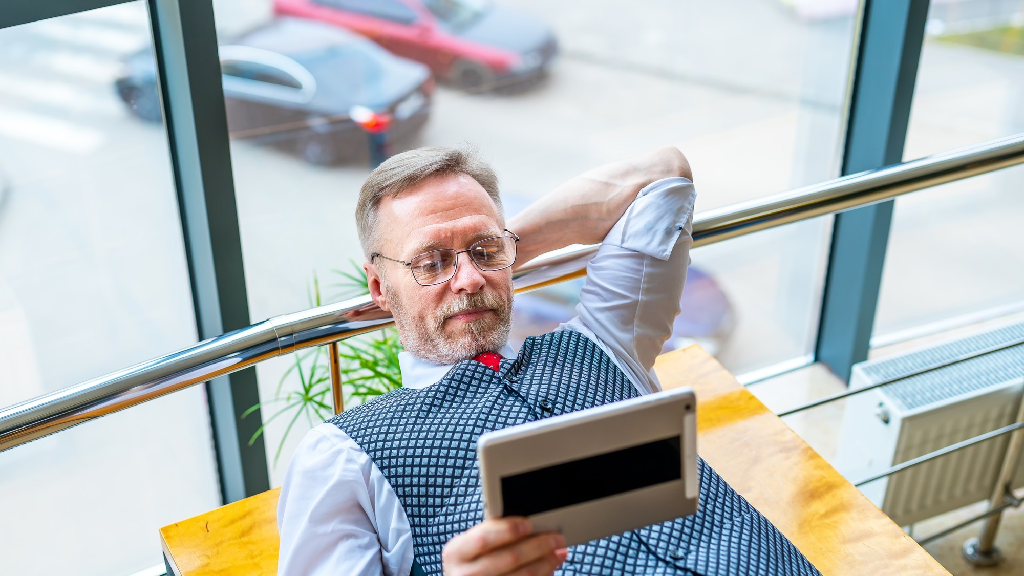 Brainstorming. Man laying at table with tablet in hands. Searching for ideas in internet. The concept of business, computer work, distant work freelance.