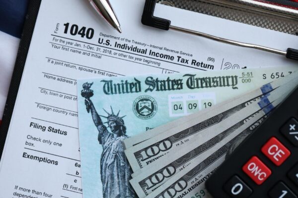 United States 1040 tax form individual income tax return with refund check and US dollar bills